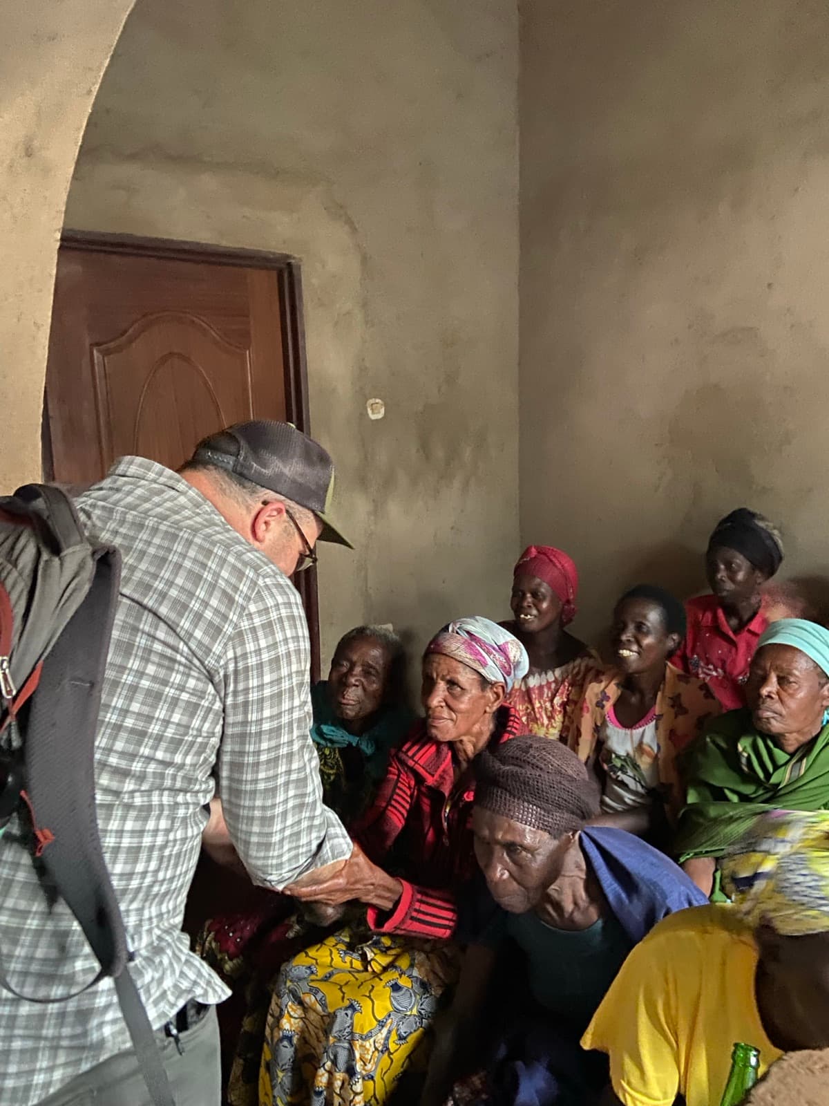 A visitor greeting a group of older women seated together during a community wellbeing session in Ngamba.